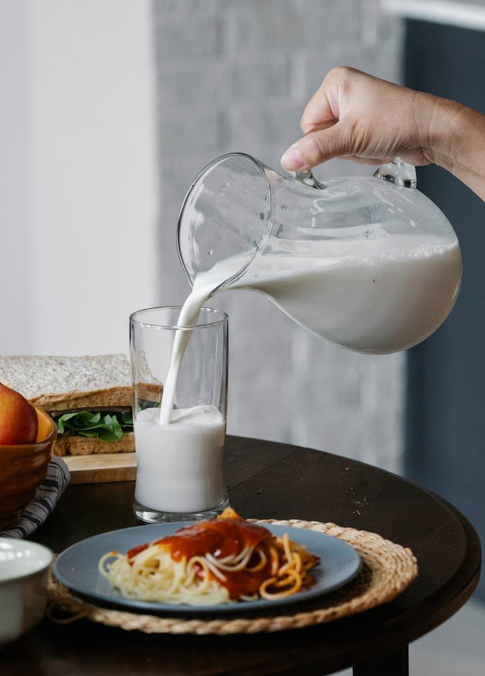 Crop person pouring milk in glass